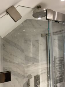 a shower with a glass door and brushed nickel hinges