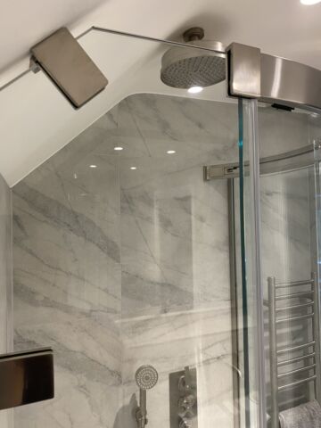 a shower with a glass door and brushed nickel hinges