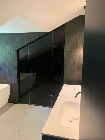 a bespoke shower with black glass