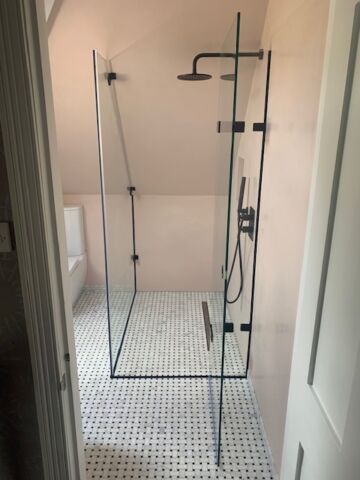 a shower in a bathroom with black hinges