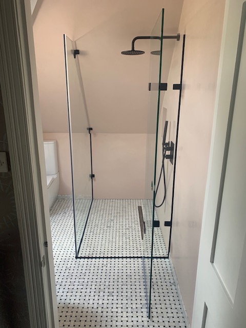 a shower in a bathroom with black hinges