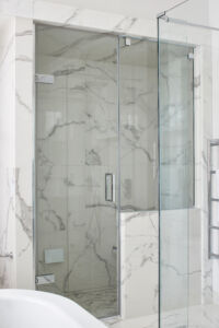 a glass shower with a marble wall