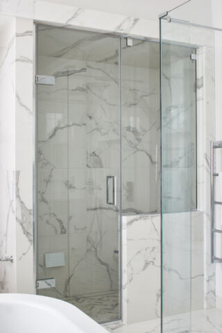 a glass shower with a marble wall