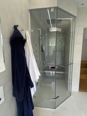 a shower with a glass door and a towel on the wall