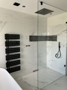 a wet room with glass shower screen and black hinges