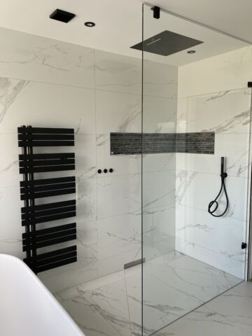 a wet room with glass shower screen and black hinges