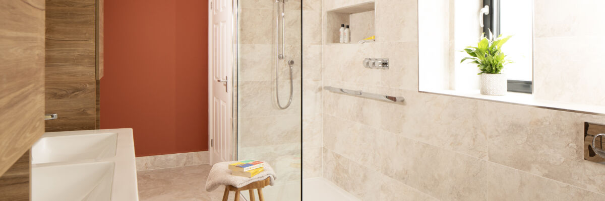 a bathroom with a glass shower screen and red wall