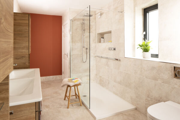 a bathroom with a glass shower screen and red wall