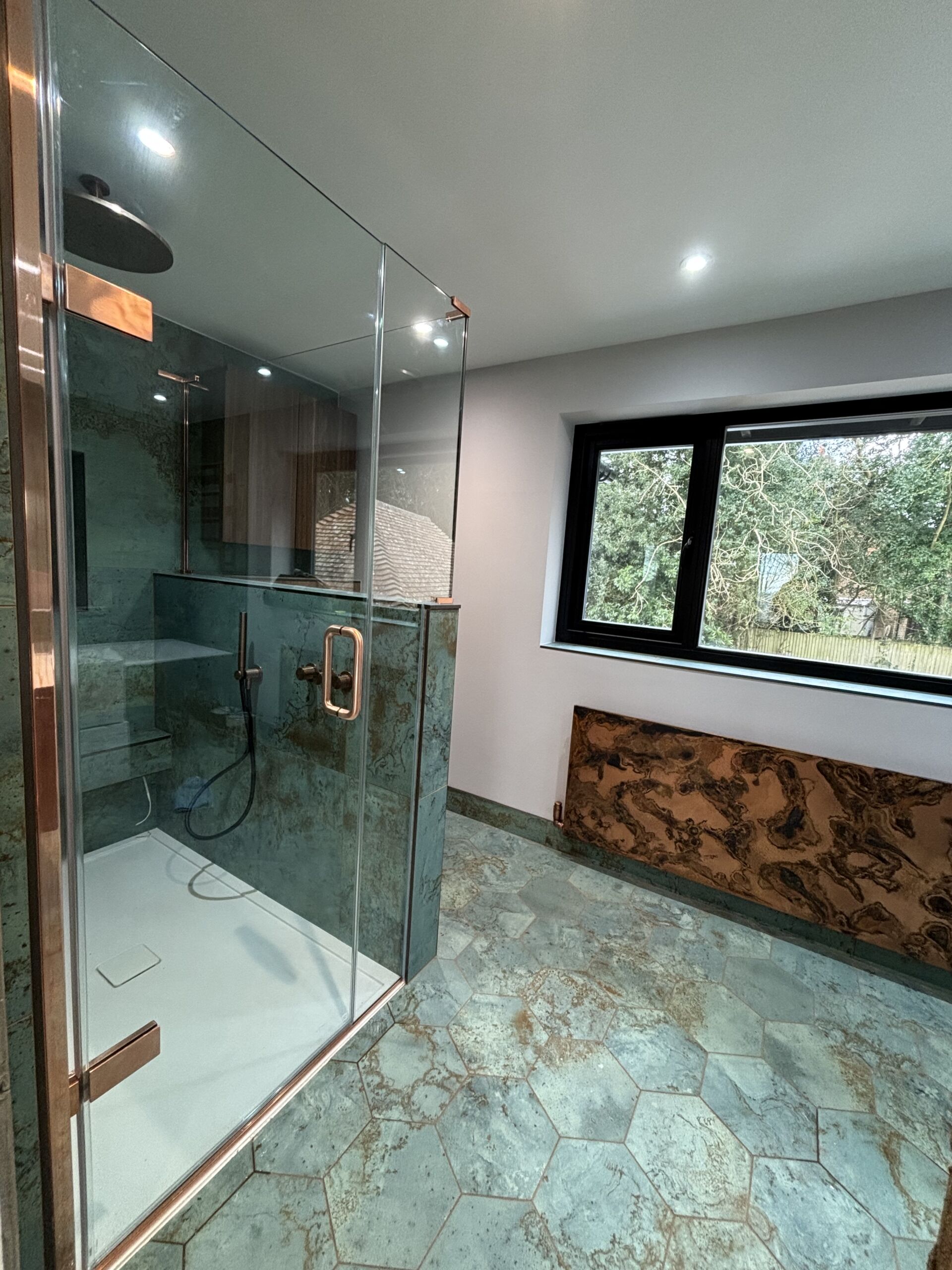 a bathroom with a glass shower and copper hinges