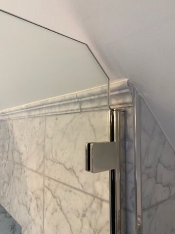 a glass door hinge on a tile wall